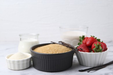 Photo of Different ingredients for panna cotta. Milk, sugar, vanilla and strawberries on white marble table, closeup