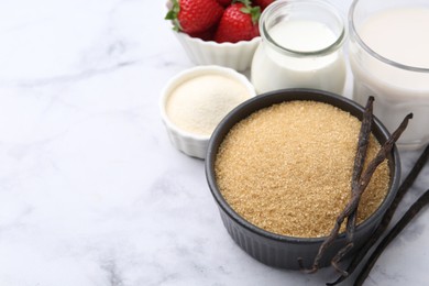Photo of Different ingredients for panna cotta. Milk, sugar, vanilla and strawberries on white marble table, closeup. Space for text