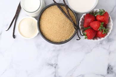 Photo of Different ingredients for panna cotta. Milk, sugar, vanilla and strawberries on white marble table, flat lay. Space for text