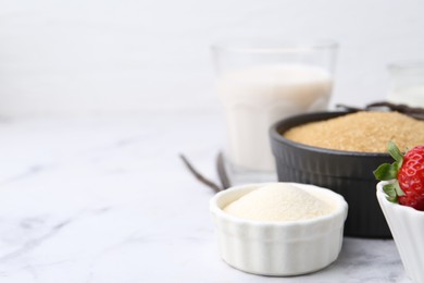 Photo of Different ingredients for panna cotta. Milk, sugar, vanilla and strawberries on white marble table, closeup. Space for text