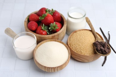 Photo of Different ingredients for panna cotta. Milk, sugar, vanilla, chocolate and strawberries on white tiled table, closeup