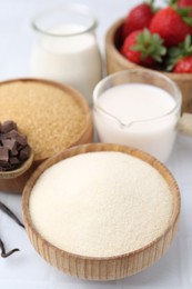 Photo of Different ingredients for panna cotta. Milk, sugar, vanilla, chocolate and strawberries on white tiled table, closeup