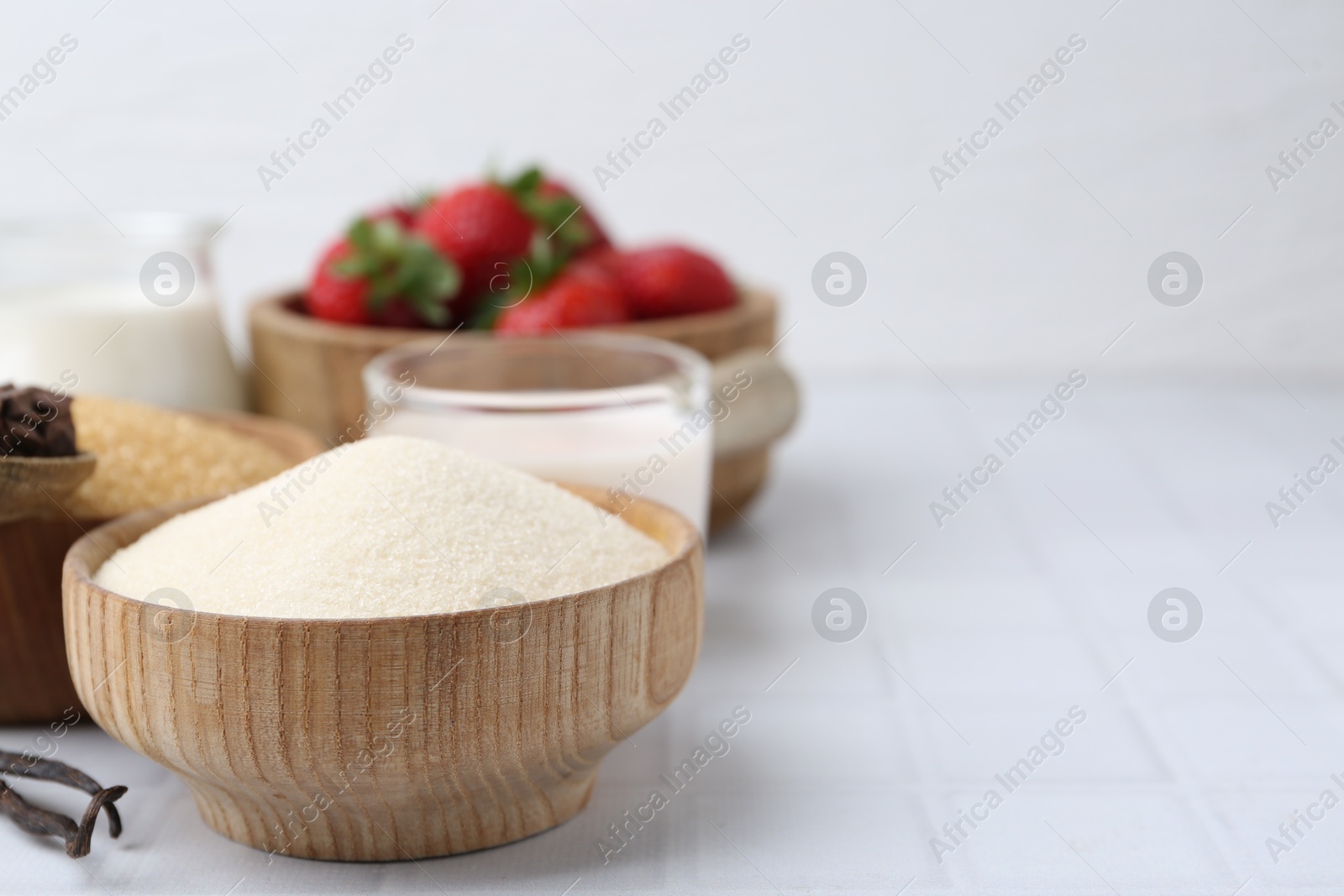 Photo of Different ingredients for panna cotta. Milk, sugar, vanilla, chocolate and strawberries on white tiled table, closeup. Space for text