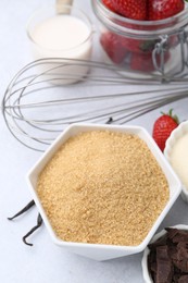 Photo of Different ingredients for panna cotta. Milk, sugar, vanilla, chocolate and strawberries on white table, closeup