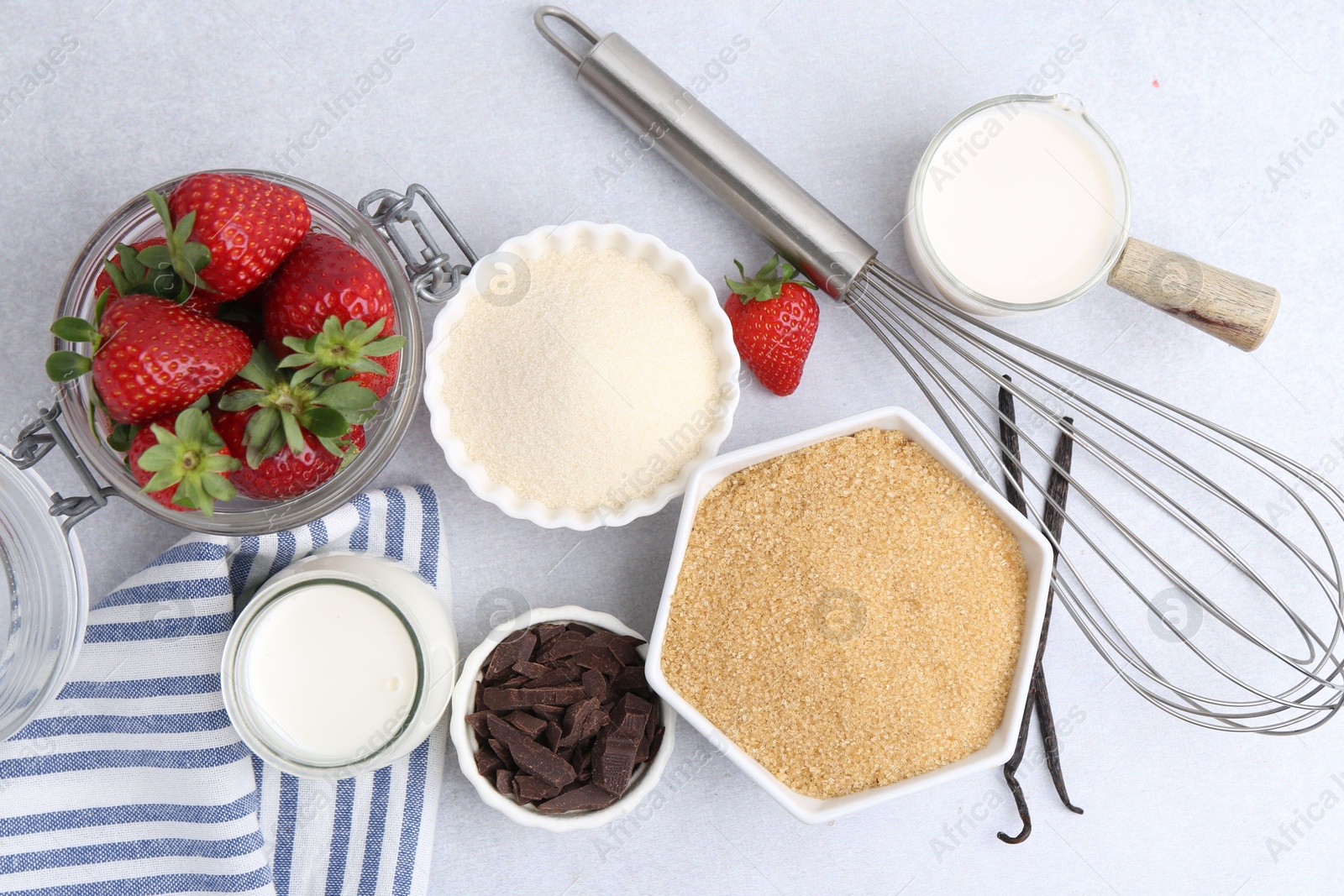Photo of Different ingredients for panna cotta. Milk, sugar, vanilla, chocolate and strawberries on white table, flat lay