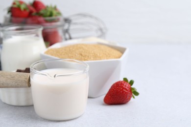 Photo of Different ingredients for panna cotta. Milk, sugar, vanilla and strawberries on white table, closeup
