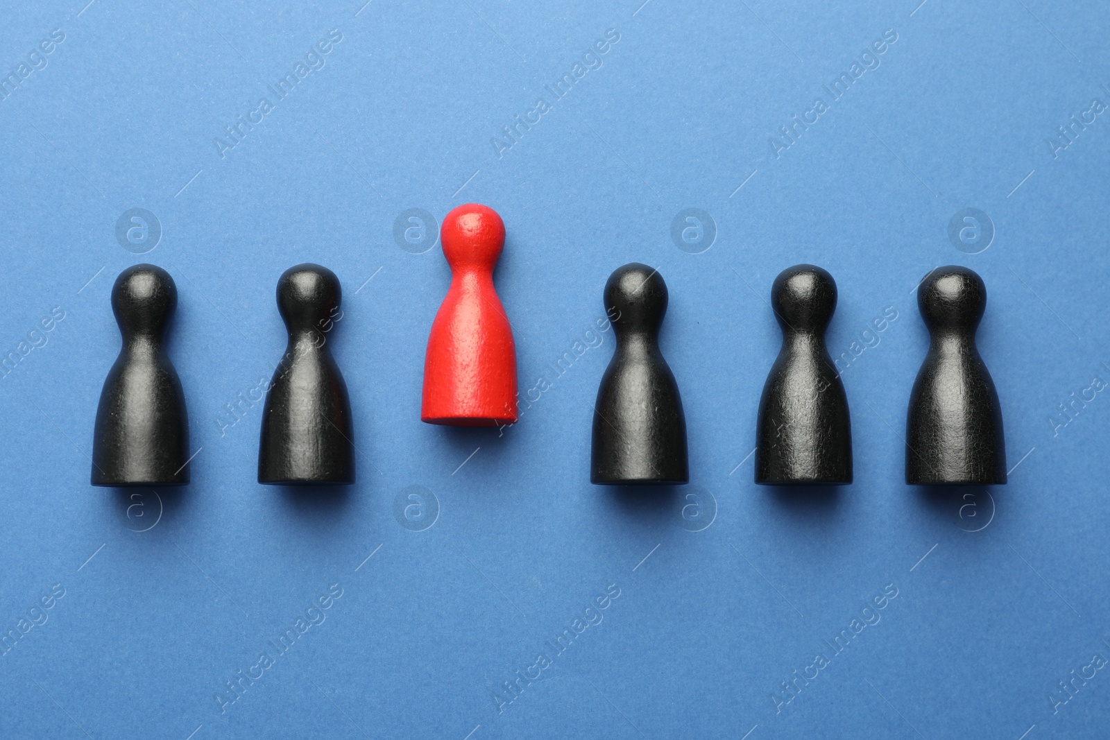 Unemployment. One red figure among black on blue background, flat lay Photo of Unemployment. One red figure among black on blue background, flat lay