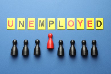 Photo of Word Unemployed and human figures on blue background, flat lay