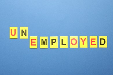 Photo of Word Unemployed on blue background, top view