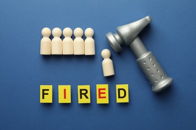 Photo of Dismissal. Word Fired, hammer and human figures on blue background, flat lay