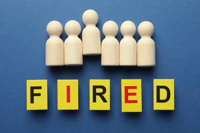 Photo of Dismissal. Word Fired and human figures on blue background, flat lay