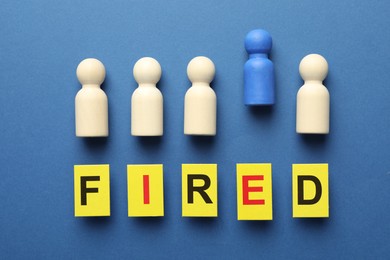 Photo of Dismissal. Word Fired and human figures on blue background, flat lay