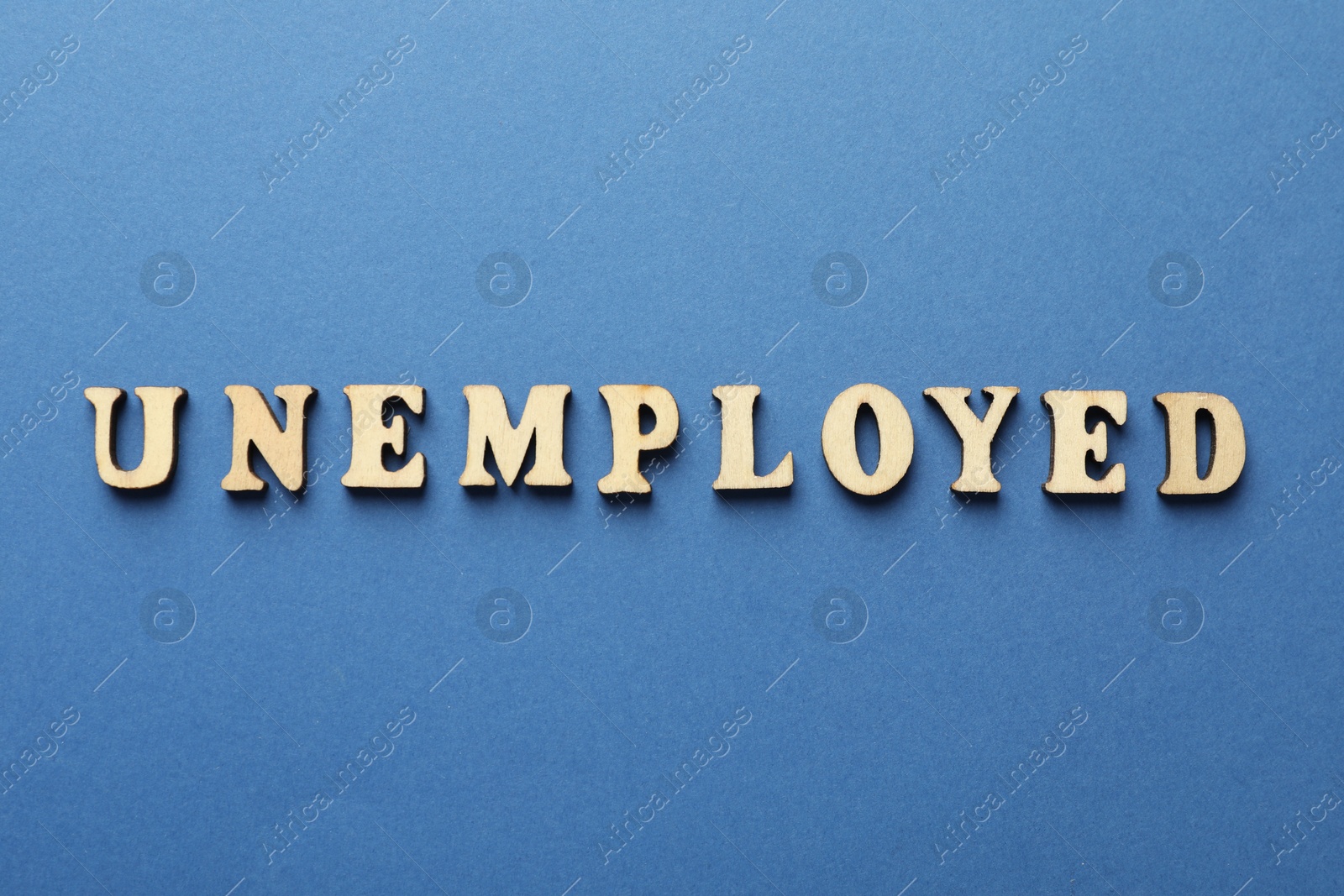 Photo of Word Unemployed on blue background, top view