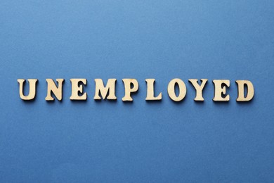 Photo of Word Unemployed on blue background, top view