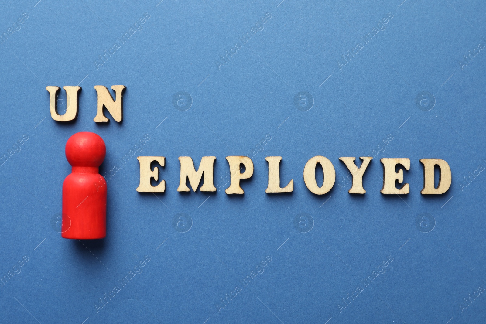 Photo of Word Unemployed and human figure on blue background, flat lay