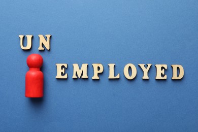 Photo of Word Unemployed and human figure on blue background, flat lay
