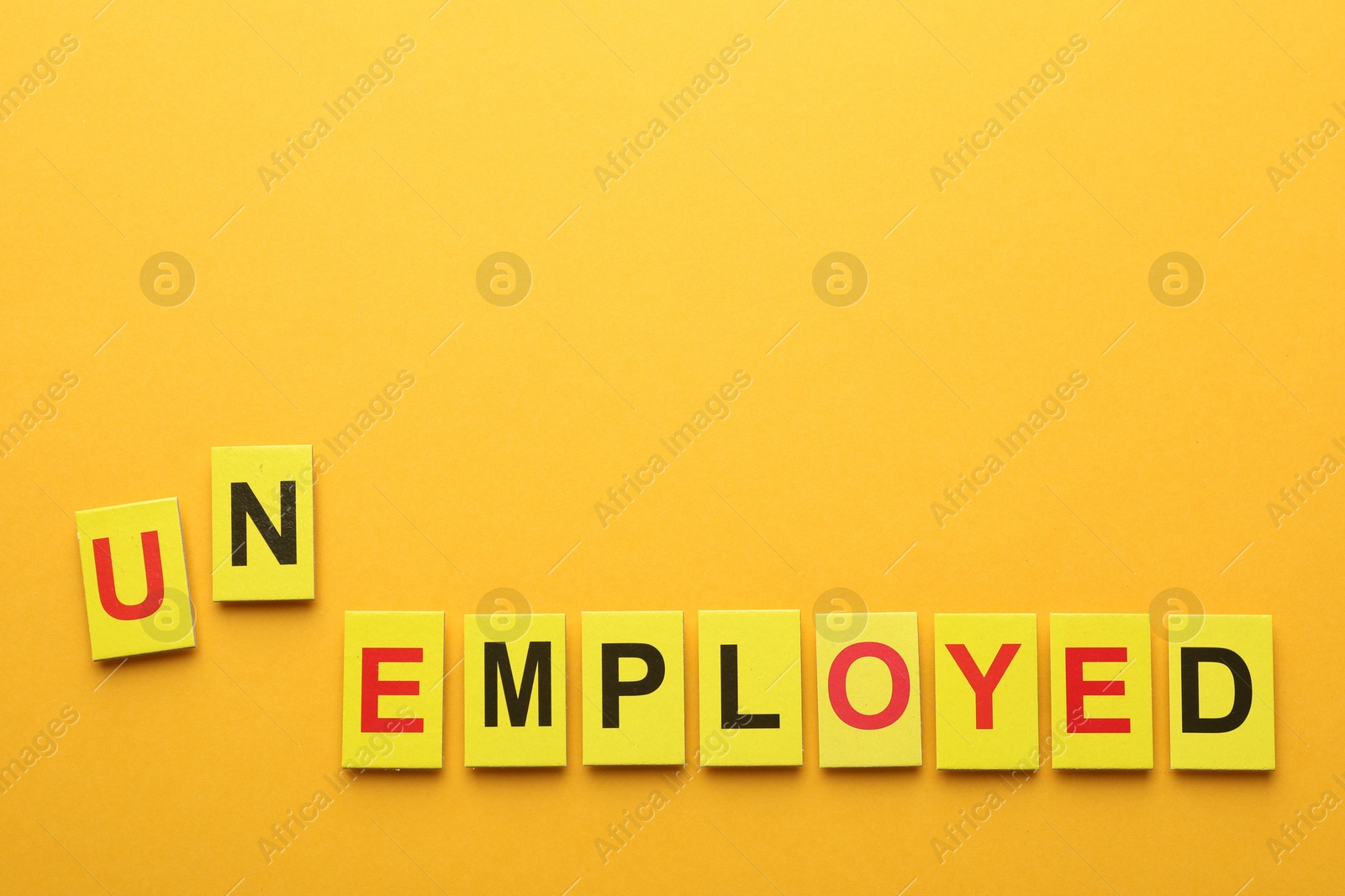 Photo of Word Unemployed on yellow background, top view. Space for text