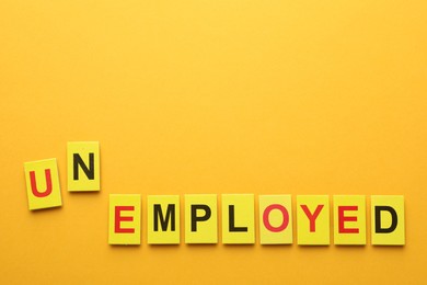 Photo of Word Unemployed on yellow background, top view. Space for text