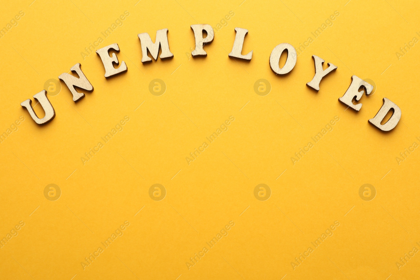 Photo of Word Unemployed on yellow background, top view. Space for text
