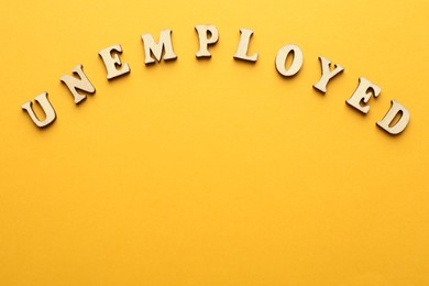 Photo of Word Unemployed on yellow background, top view. Space for text