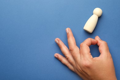 Photo of Dismissal. Woman throwing human figure away on blue background, top view. Space for text
