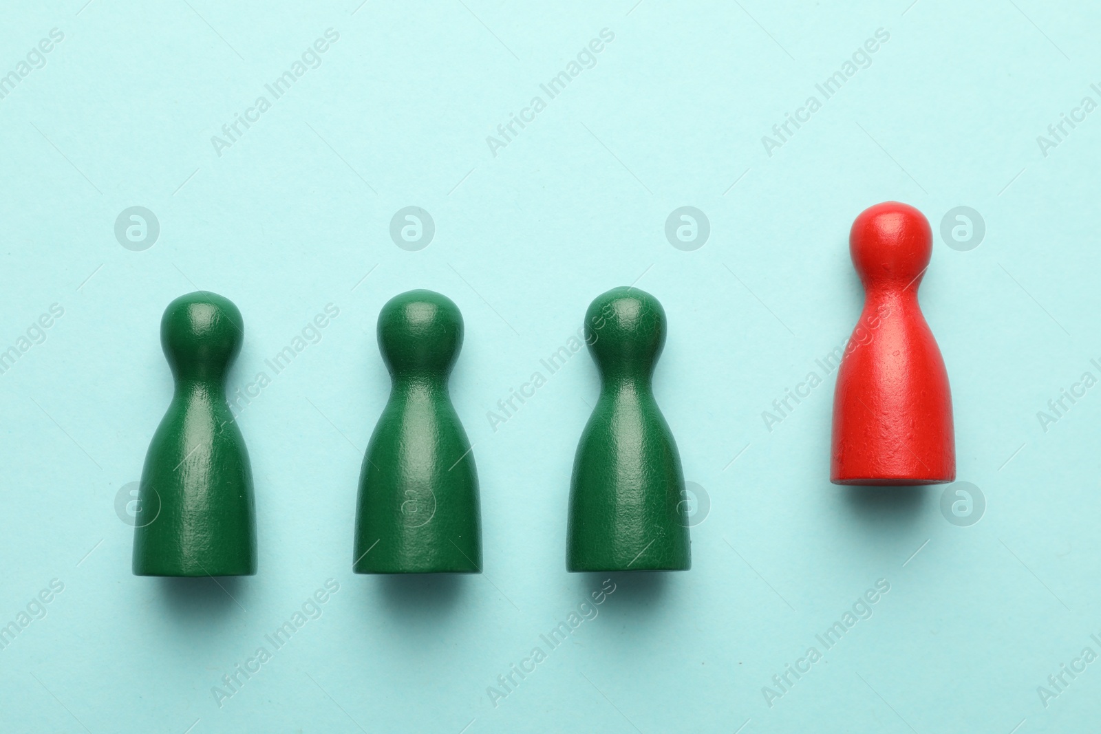 Unemployment. One red figure among green on light blue background, flat lay Photo of Unemployment. One red figure among green on light blue background, flat lay