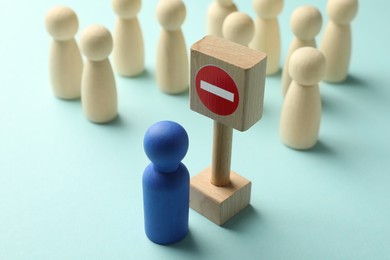 Photo of Unemployment. Human figures and stop sign on light blue background, closeup