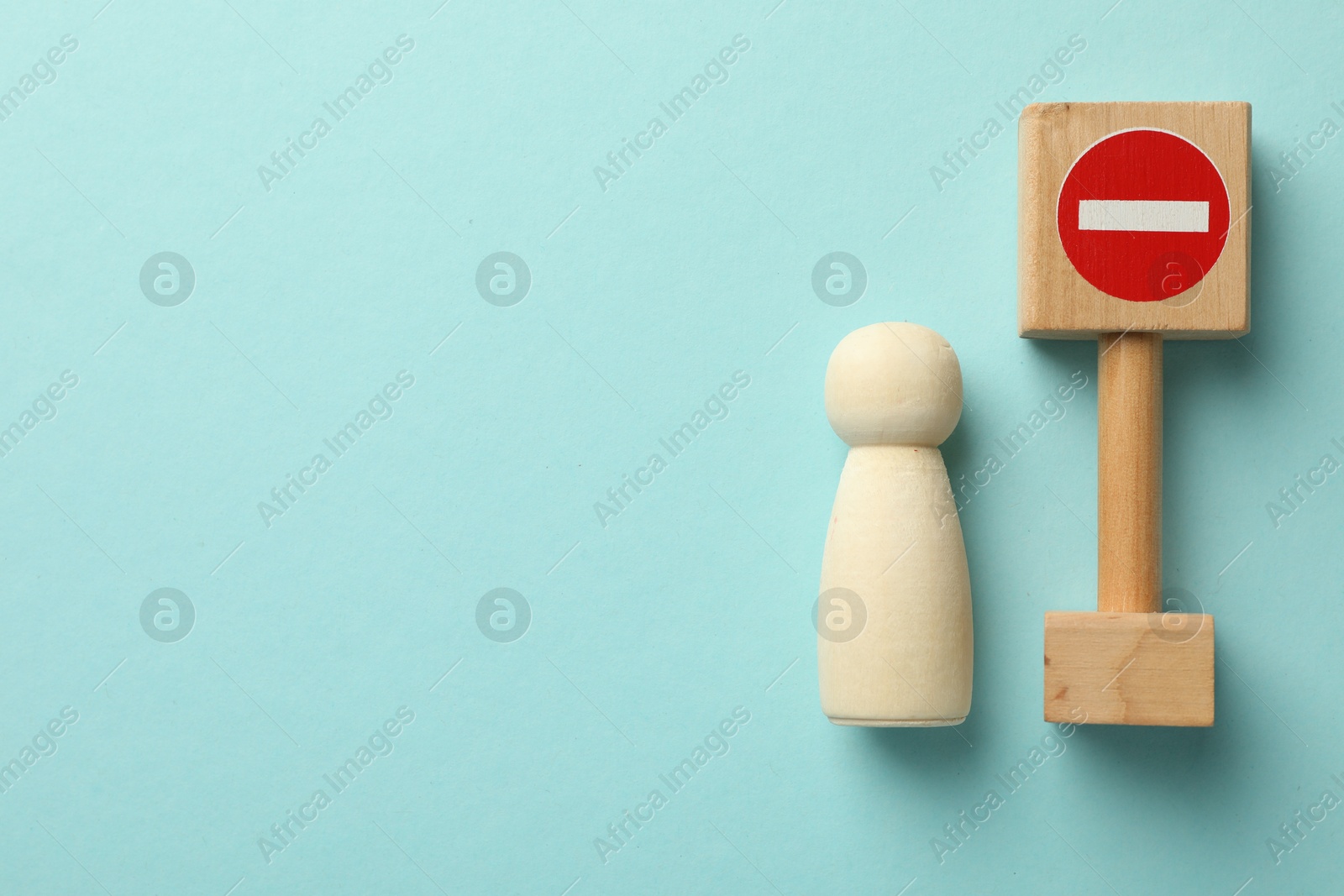 Unemployment. Human figure and stop sign on light blue background, top view. Space for text Photo of Unemployment. Human figure and stop sign on light blue background, top view. Space for text