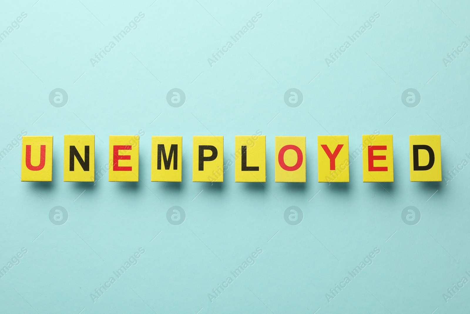 Word Unemployed on light blue background, top view Photo of Word Unemployed on light blue background, top view