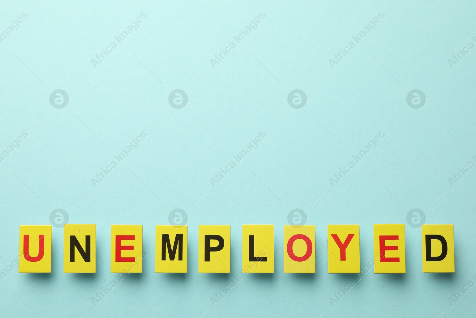 Word Unemployed on light blue background, top view. Space for text Photo of Word Unemployed on light blue background, top view. Space for text