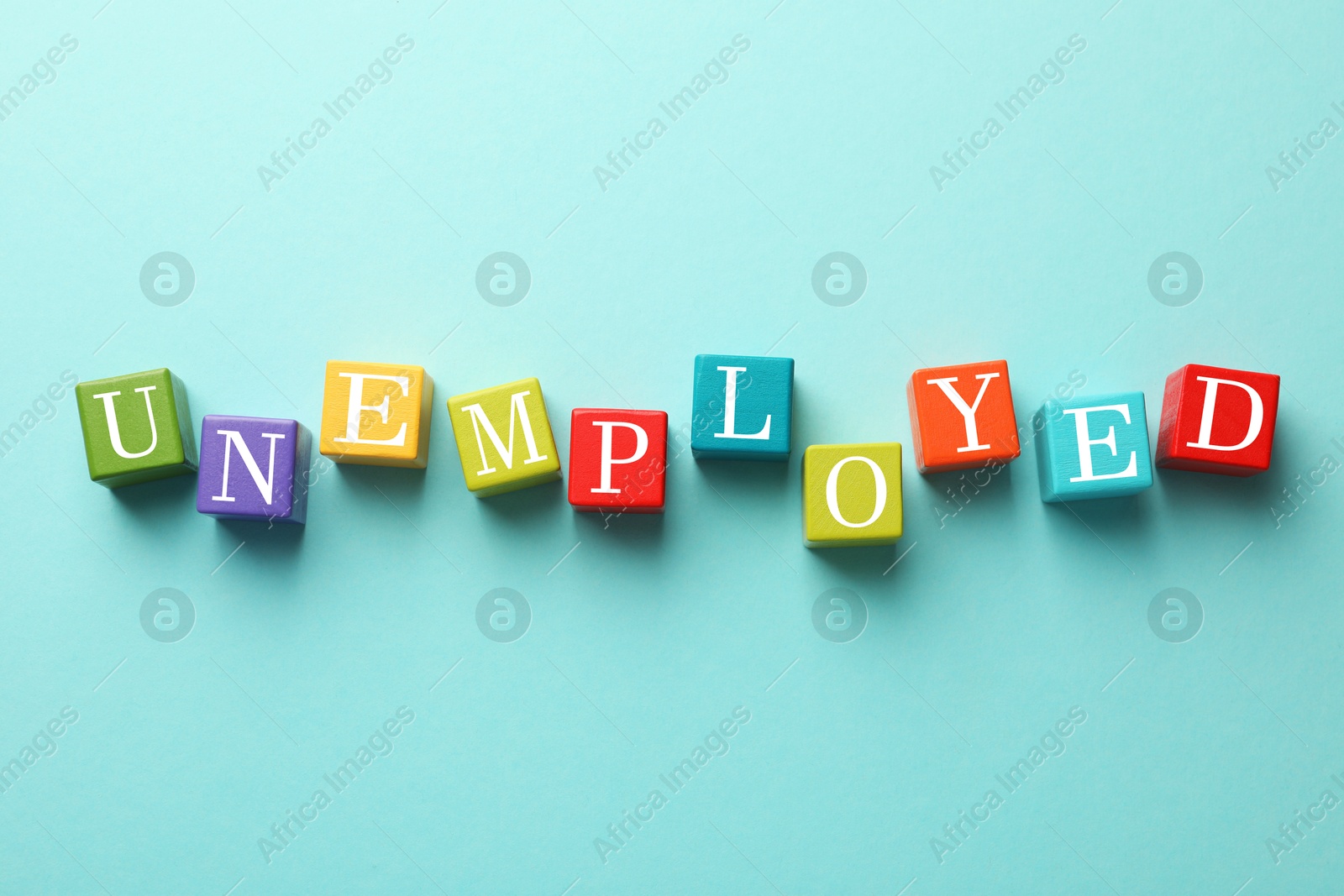 Photo of Unemployment. Colorful cubes on light blue background, flat lay