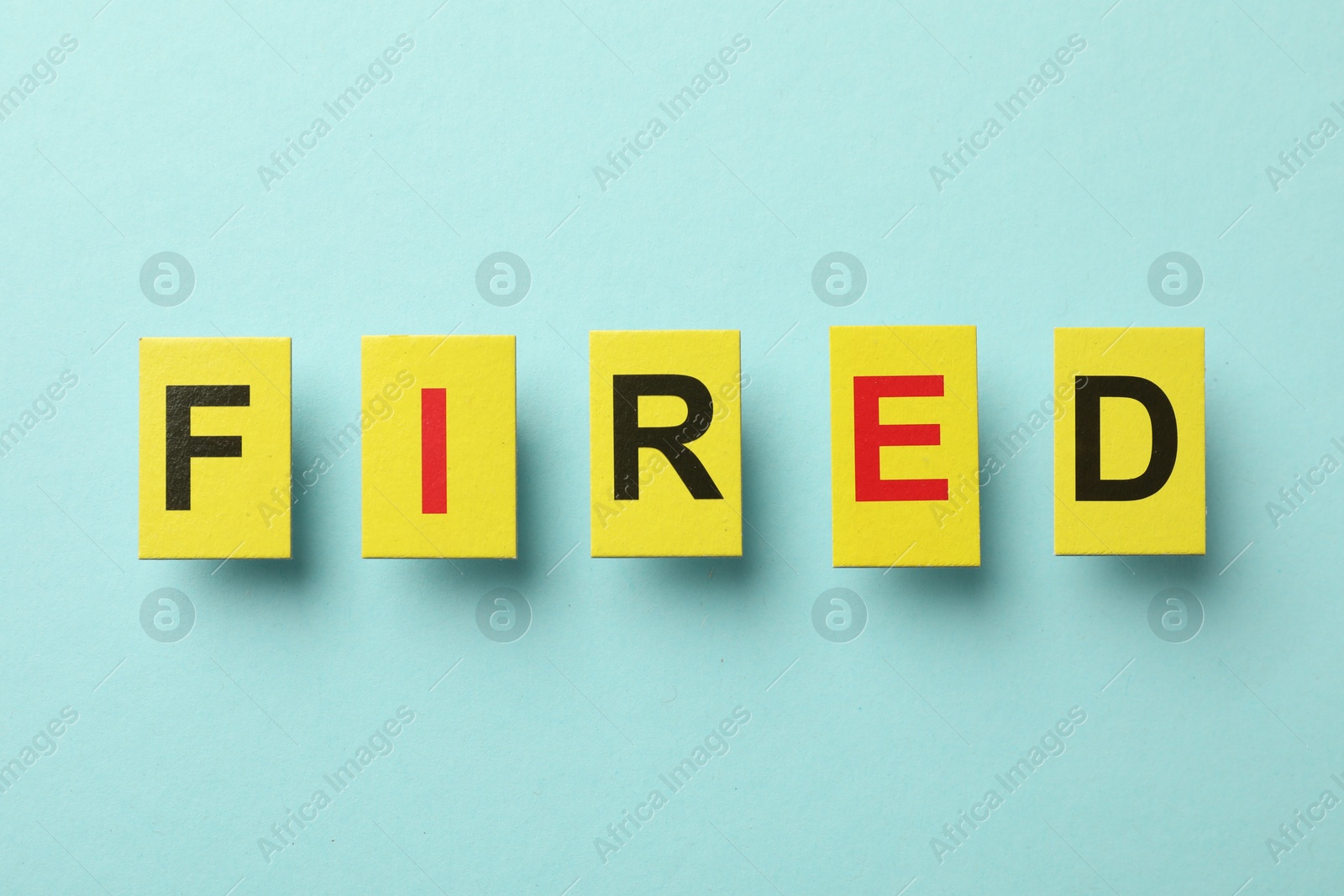 Photo of Dismissal. Word Fired on light blue background, top view