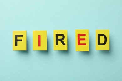 Photo of Dismissal. Word Fired on light blue background, top view