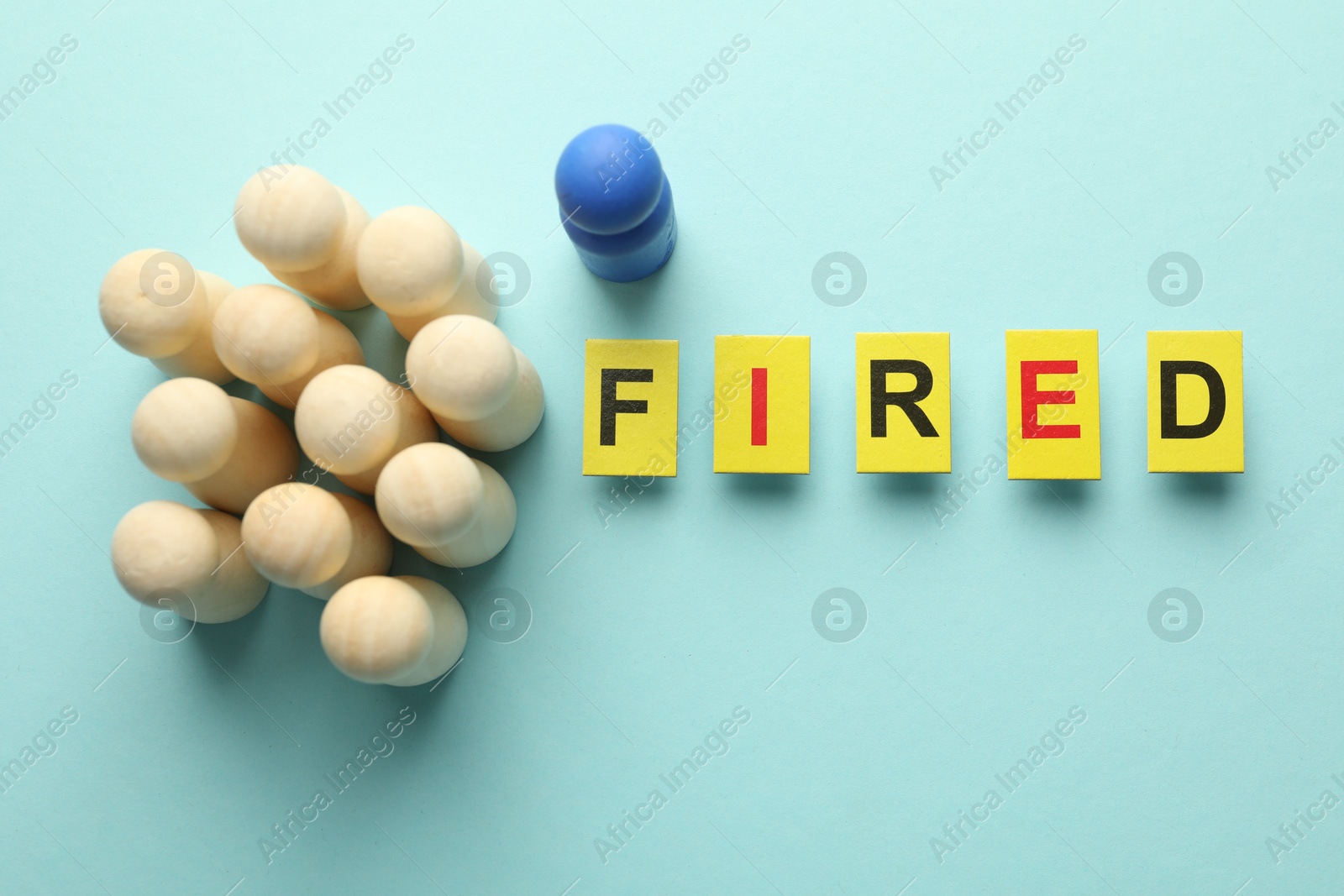 Photo of Dismissal. Word fired and human figures on light blue background, top view
