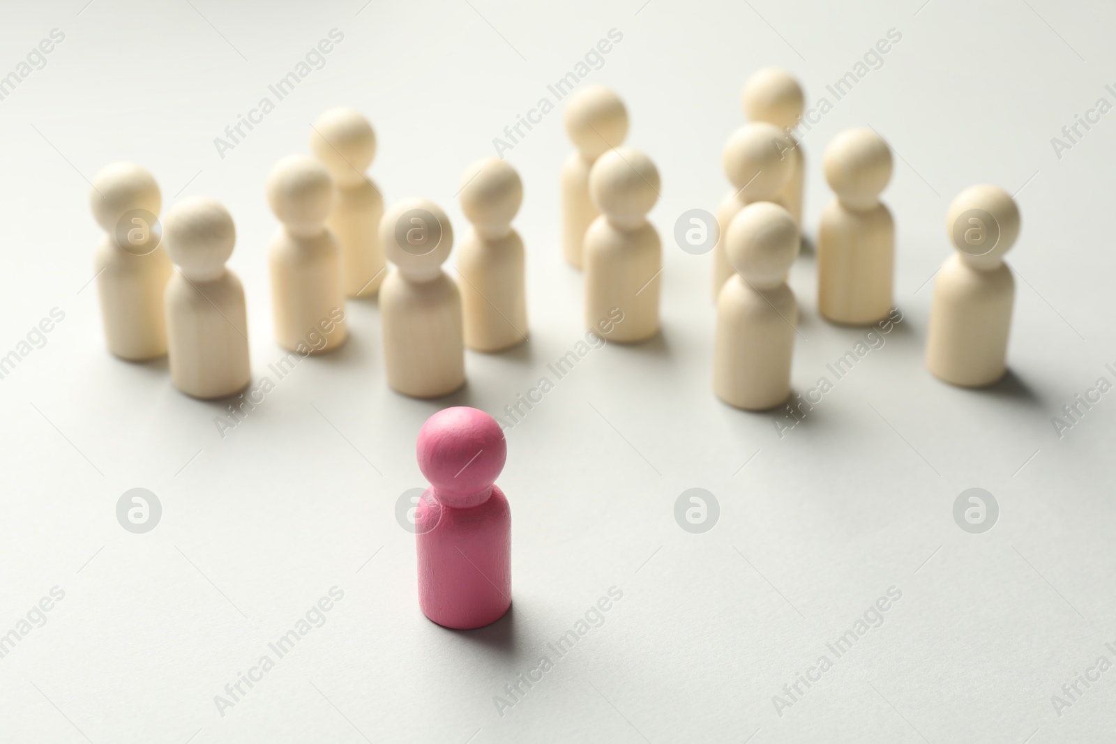 Unemployment. One pink figure among wooden on light background Photo of Unemployment. One pink figure among wooden on light background