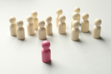 Photo of Unemployment. One pink figure among wooden on light background