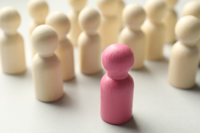 Photo of Unemployment. One pink figure among wooden on light background, closeup