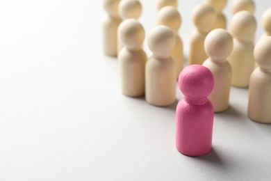Photo of Unemployment. One pink figure among wooden on light background, closeup. Space for text