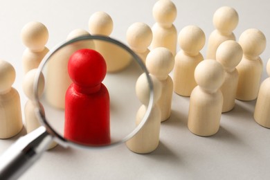 Photo of Unemployment. Human figures and magnifying glass on light background, closeup