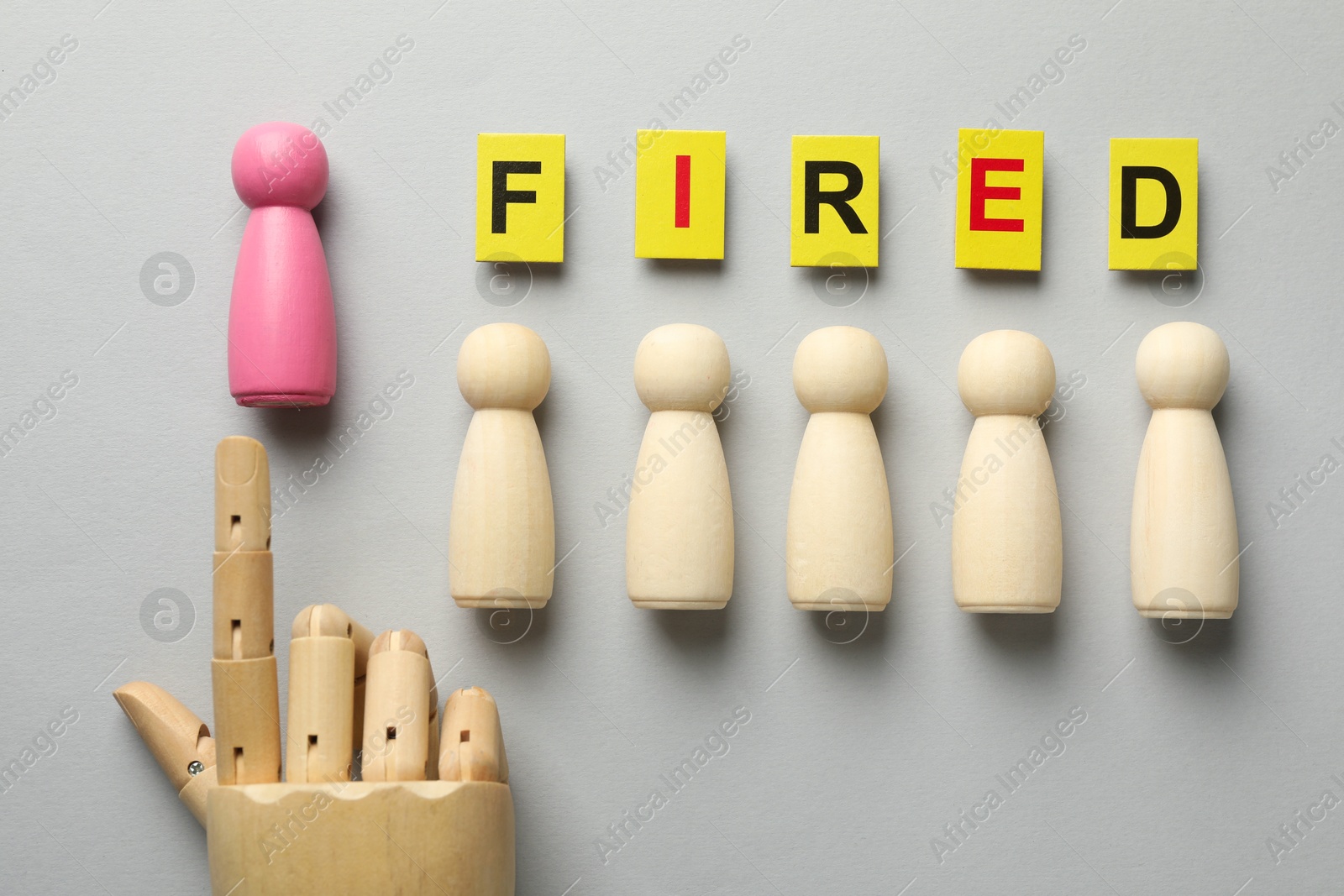 Dismissal. Word fired, human and hand figures on light background, top view Photo of Dismissal. Word fired, human and hand figures on light background, top view