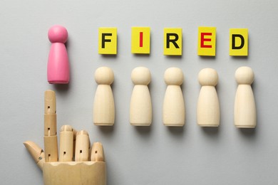 Photo of Dismissal. Word fired, human and hand figures on light background, top view