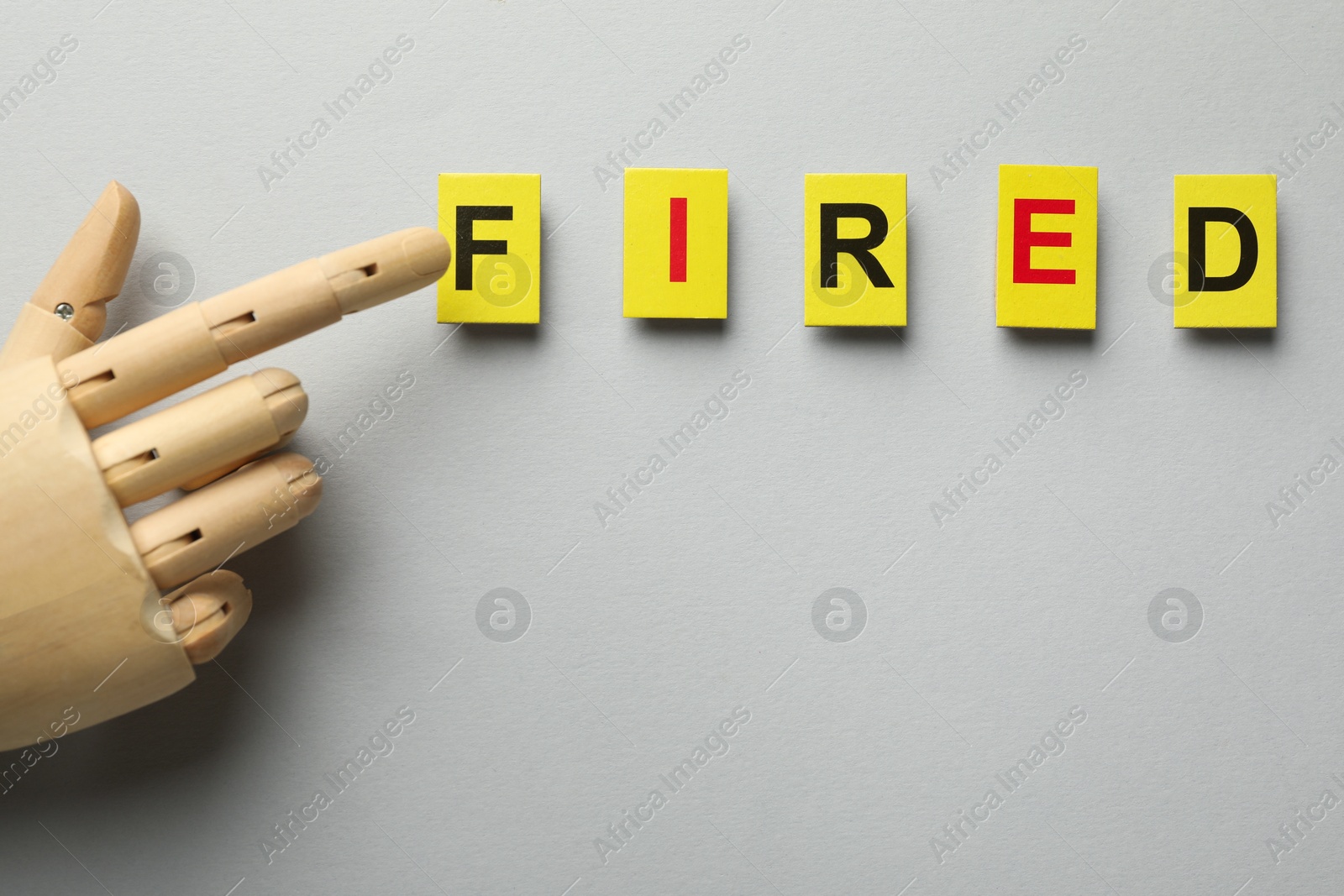 Dismissal. Word fired and hand figure on light background, top view Photo of Dismissal. Word fired and hand figure on light background, top view