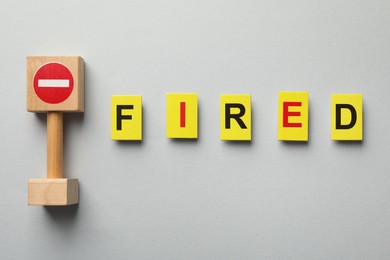 Photo of Dismissal. Word fired and stop sign on light background, top view