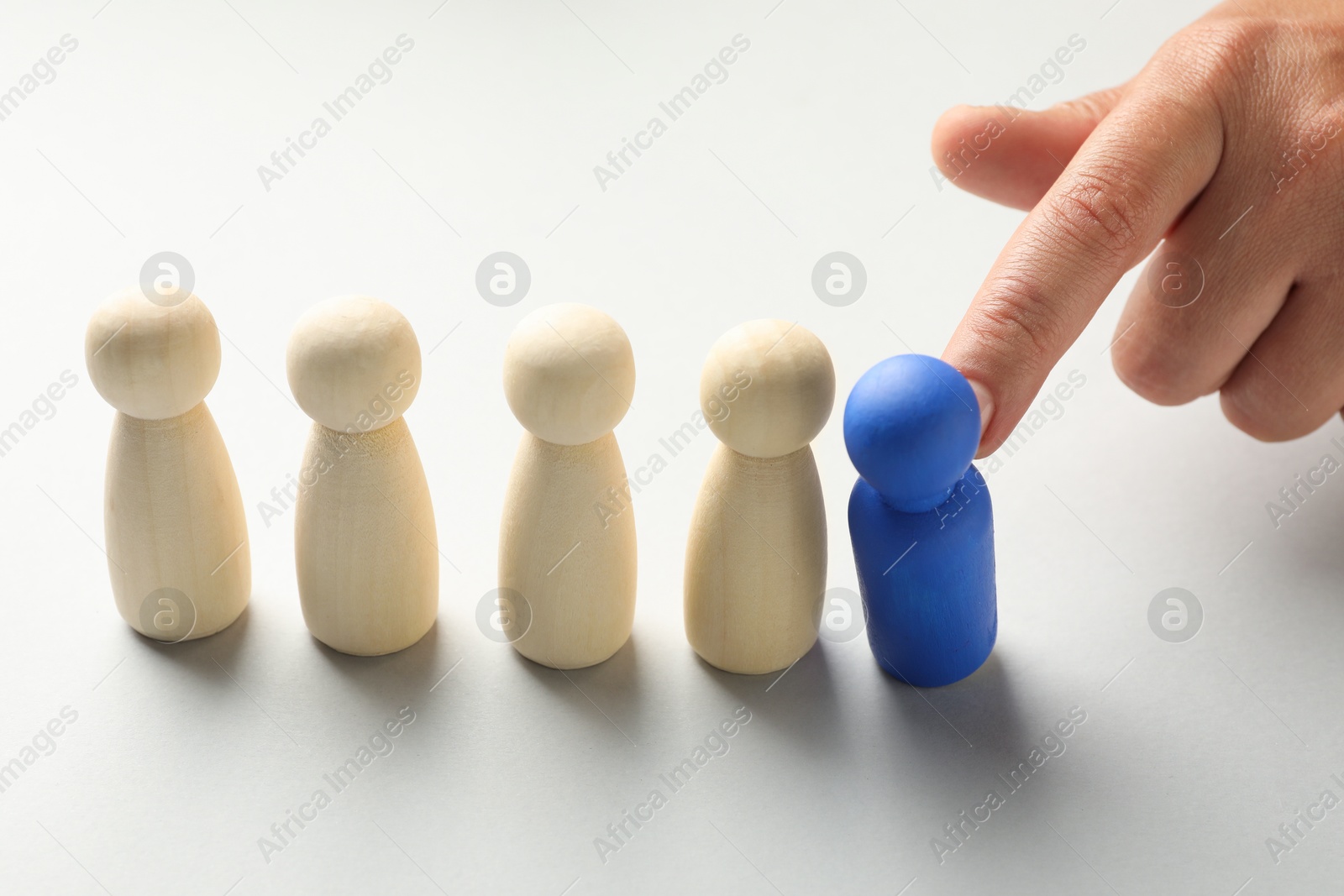 Dismissal. Woman throwing one human figure away on light background, closeup Photo of Dismissal. Woman throwing one human figure away on light background, closeup