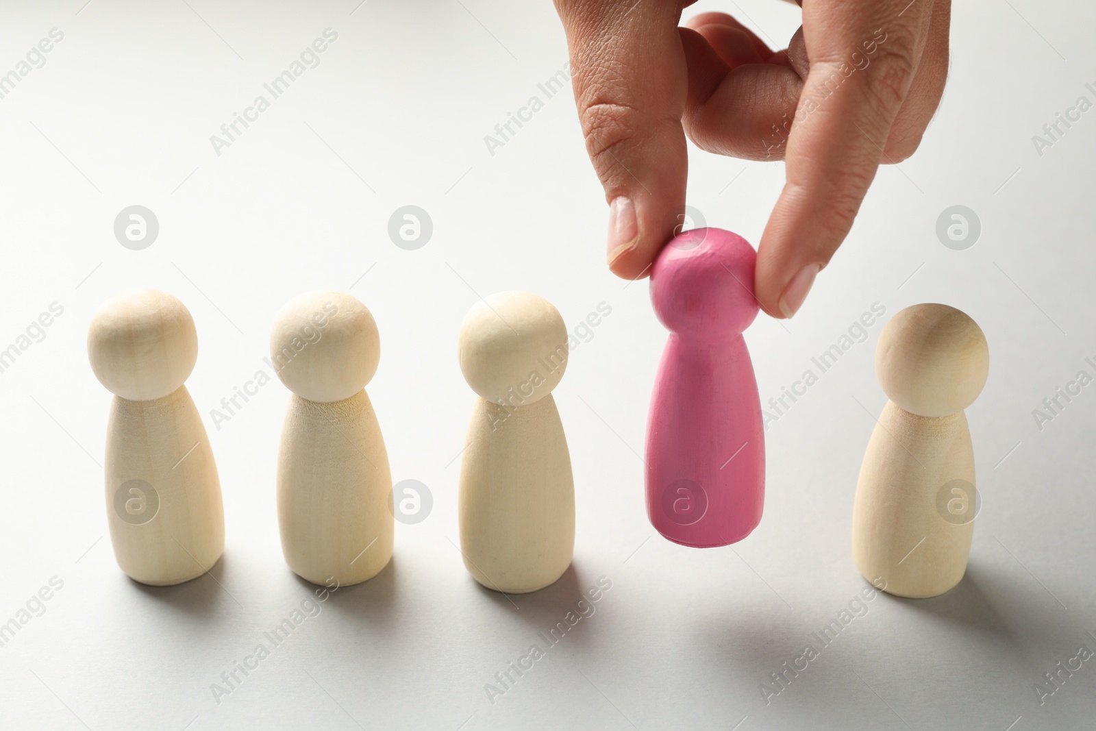 Photo of Dismissal. Woman taking one human figure away on light background, closeup