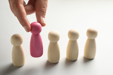 Photo of Dismissal. Woman taking one human figure away on light background, closeup
