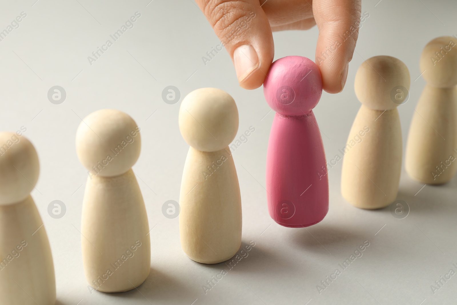 Dismissal. Woman taking one human figure away on light background, closeup Photo of Dismissal. Woman taking one human figure away on light background, closeup