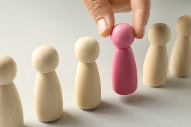 Photo of Dismissal. Woman taking one human figure away on light background, closeup