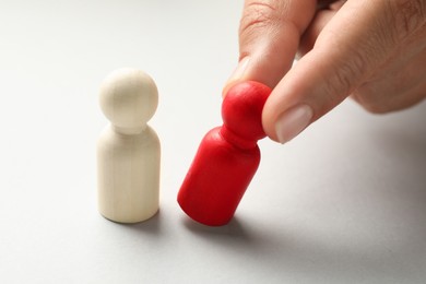 Photo of Dismissal. Woman taking one human figure away on light background, closeup