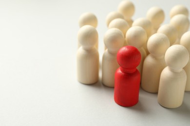 Photo of Unemployment. One red figure among wooden on light background, closeup. Space for text